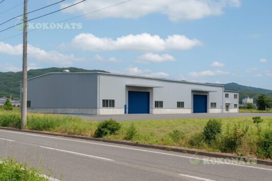 倉庫・工場 外観建築パース|鉄骨造 平屋建て 郊外の工業地域に計画された、鉄骨造平屋建ての倉庫・工場建築の外観パースです。外装には金属サイディングを採用し、シャッター付きの搬出入口を複数設けることで、物流・製造・保管など多用途に対応可能な計画としています。シンプルで合理的なボリューム構成とし、周辺環境とのスケール感や敷地条件を考慮した配置計画を3DCGで可視化しています。倉庫・工場の新築計画や事業用建築の検討、関係者間での完成イメージ共有を目的とした外観建築パースです。